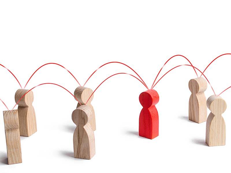 Wooden models of people, one in red, with lines joining them up representing knowledge sharing