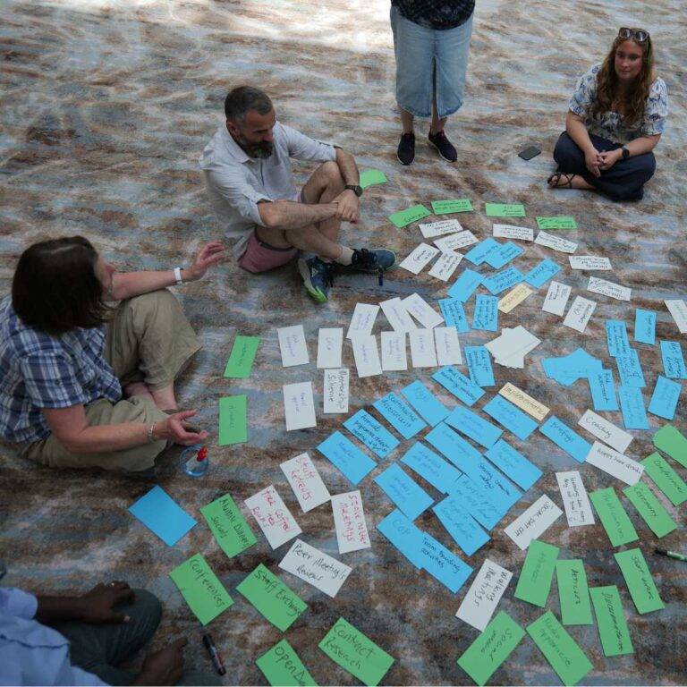 People sat on the floor working on a organising coloured card for a workshop activity